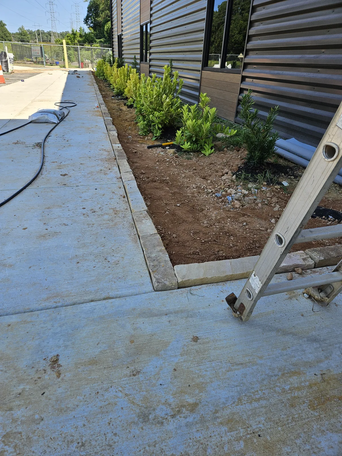 Before: Bare soil commercial planting bed before landscaping installation